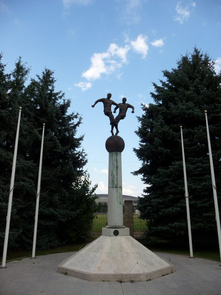 Scultpture of two footballers on an oversized football above a plinth