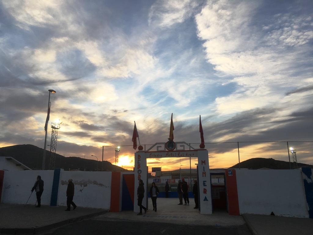 Deportiva Minera supporters walk home under a sunset