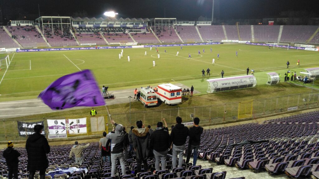 Five Timisoara supporters standing in a line, one waving a large flag