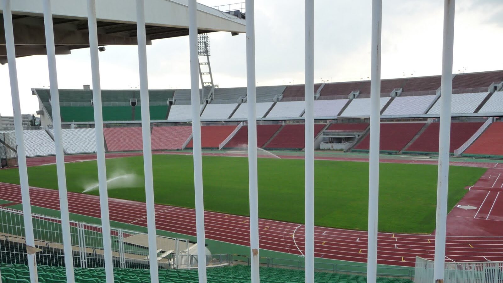 Sprinklers watering a football pitch bordered by an athletics track